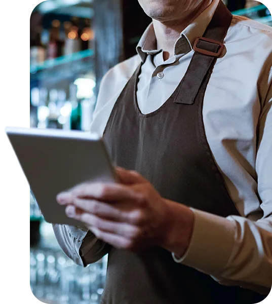 Atendente de restaurante usando o sistema F‑Rest em um tablet no balcão.